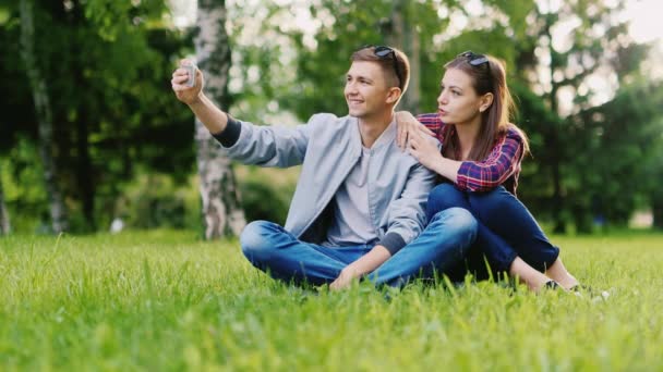 Casal jovem descansando em um parque, faz selfie — Vídeo de Stock