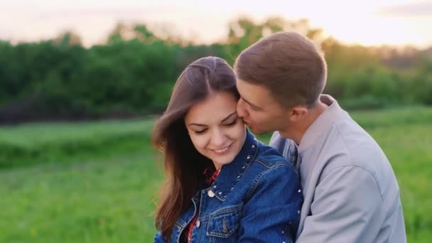 Um jovem casal a abraçar. O cara abraça e beija a menina — Vídeo de Stock