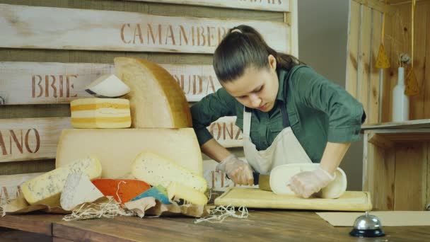 Serien av 3 video: säljaren ostarna på jobbet. Förpackningar ost, sedan ler mot kameran — Stockvideo