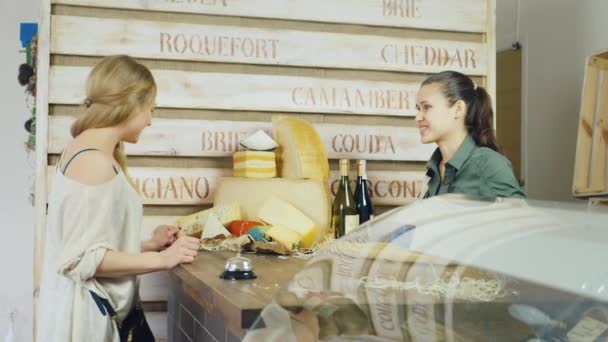 El vendedor amistoso se comunica con el comprador. Debería estar detrás del mostrador en la tienda de queso. Pan tiro — Vídeos de Stock