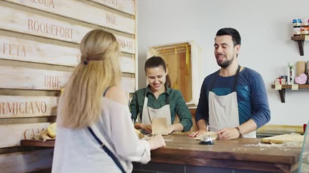 Ψώνια στο κατάστημα τυρί. Πίσω από τον πάγκο εργασίας άνδρα και γυναίκας φιλικό χαμόγελο. — Αρχείο Βίντεο