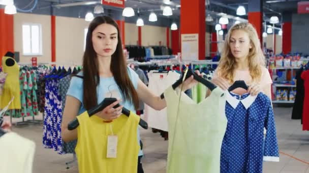 Dos mujeres jóvenes mirando ropa nueva de verano en el espejo — Vídeos de Stock