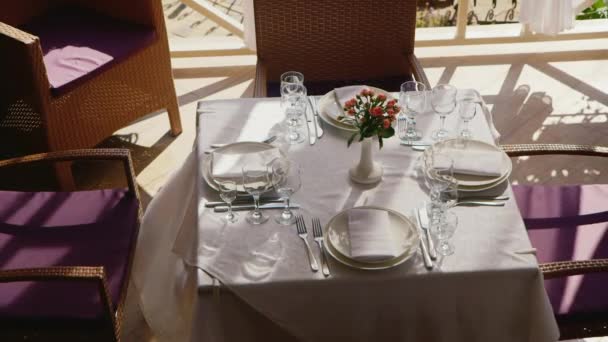 La mesa en el restaurante de verano. El sol brilla, las cortinas se balancean en el viento . — Vídeos de Stock