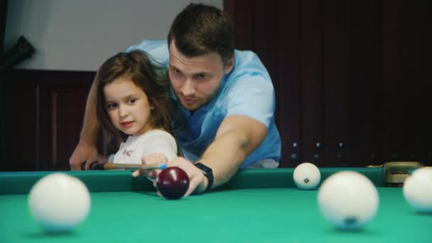 Papá le enseña a su hija a jugar billar. Muestra cómo mantener la señal — Vídeo de stock