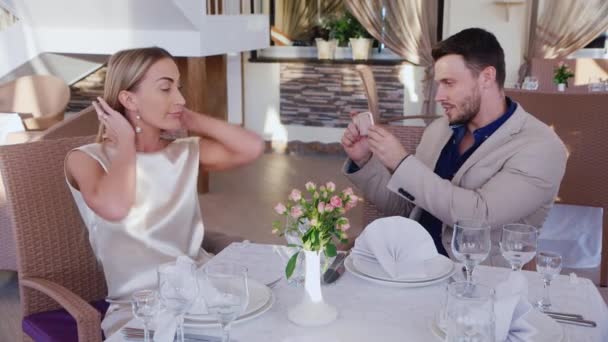 Mann fotografiert Frau am Telefon. an einem Tisch in einem Restaurant sitzen — Stockvideo