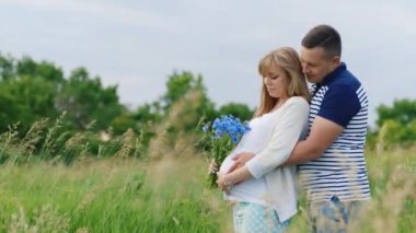 Mutlu aile - adam hamile karısını arkadan sarılma. Park veya alan olduğunu