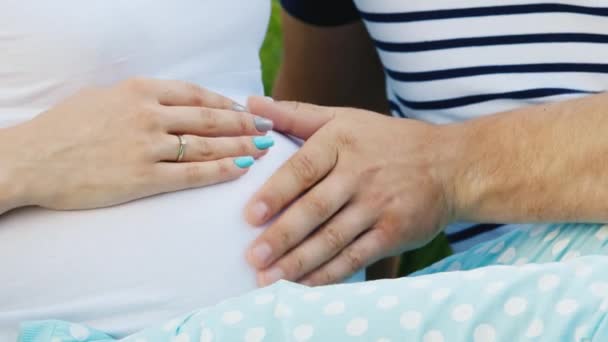 Руки чоловіка і дружини на великому животі вагітної жінки — стокове відео