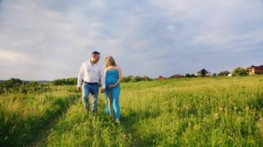 Mutlu genç aile bir yürüyüş. Annem bir bebek, hamile bir kadın ve kocası yürüyüş bekliyor