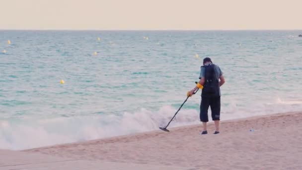 Lloret de Mar, Espanha - 15 de junho de 2016: Homem com detector de metais à procura de moedas e objetos de valor na praia — Vídeo de Stock