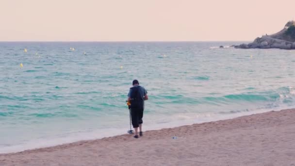 Lloret de Mar, Spain - June 15, 2016: Man with metal detector looking for coins and valuables on the beach — Stock Video