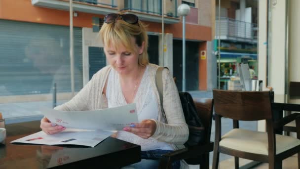 Młoda kobieta czytanie menu w kawiarni. — Wideo stockowe