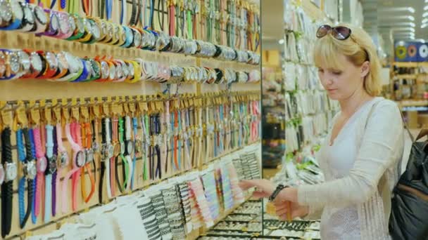 Mujer joven probándose relojes en la tienda para los turistas — Vídeos de Stock