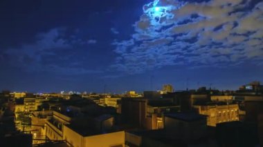 Ayın yükselişine şehir ve evlerin çatıları üzerinde. Şafak için Timelapse akşam. Şehrin üzerinde güneş doğar