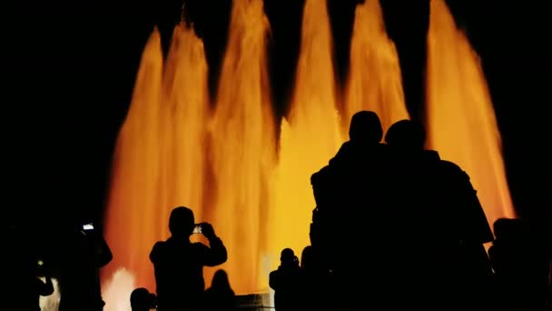 Recognizable silhouettes of people in singing fountain in Barcelona. People watching the show, photographed fountain — Stock Video