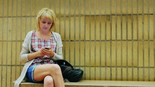 Young woman uses phone to the metro station. Waiting for the train — Stock Video