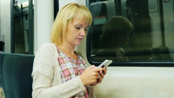 Женщина идет к вагону метро, печатает на мобильном телефоне — стоковое видео
