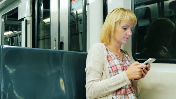 Eine junge Frau liest eine Nachricht am Telefon und geht zur U-Bahn — Stockvideo