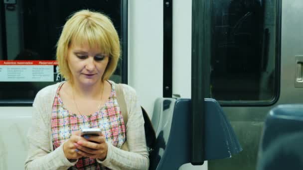 Una mujer va al vagón del metro, escribiendo en el teléfono móvil — Vídeo de stock