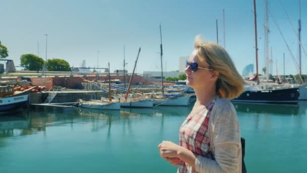 Steadicam-Aufnahme: Eine Touristin spaziert mit Yachten an den Docks entlang. Barcelona, Spanien — Stockvideo