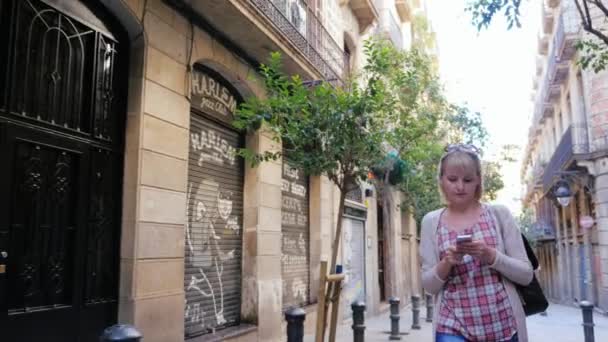 Barcelona, Espanha - 15 de junho de 2016: Mulher caminhando pelas ruas estreitas do bairro gótico, olhando para a tela do smartphone — Vídeo de Stock