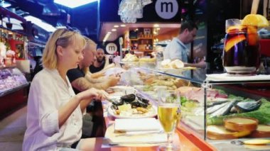 Barcelona, İspanya - 15 Haziran 2016: Ziyaretçiler deniz ürünleri yemek yemek, sayaç oturup. Barcelona'da ünlü Boqueria market