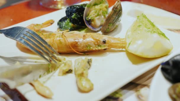 Крупный план - есть морепродукты. На тарелке нож режет моллюска — стоковое видео