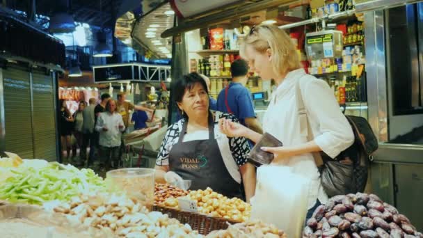 Barcelona, Spanien - 15. Juni 2016: Eine Frau kauft Süßigkeiten auf dem berühmten Boqueria-Markt — Stockvideo