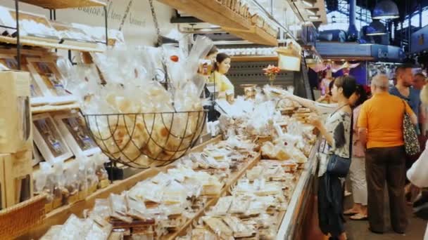 Barcelona, España - 15 de junio de 2016: Los compradores miran los dulces en el mostrador grande hermosa. El famoso mercado de la Boquería — Vídeo de stock