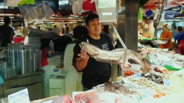 Barcelona, España - 15 de junio de 2016: Los vendedores están trabajando detrás del departamento de pesca de mostrador, vendiendo y pesando pescado. El famoso mercado de la Boquería — Vídeo de stock