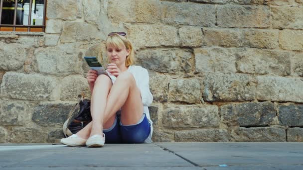 Touriste femme est assis aux murs de la vieille maison : regarder la carte ou le guide — Video