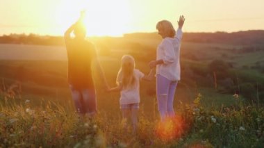 İki çocuk - bir kız ve bir erkek mutlu bir şekilde atlama ve güneş ellerini sallayarak anne