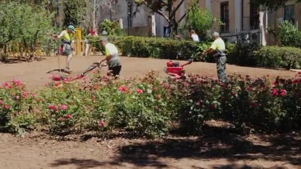 Barcelona, Spanien - 20 juni 2016: Trädgårdsmästare sköter gräsmattan, odla marken. Nära promenader turister. Några av berömda Sagrada Familia — Stockvideo