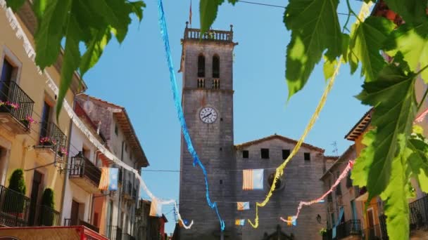 Torre del reloj en una antigua iglesia en un pequeño pueblo español. Banderas colgadas de Cataluña — Vídeos de Stock