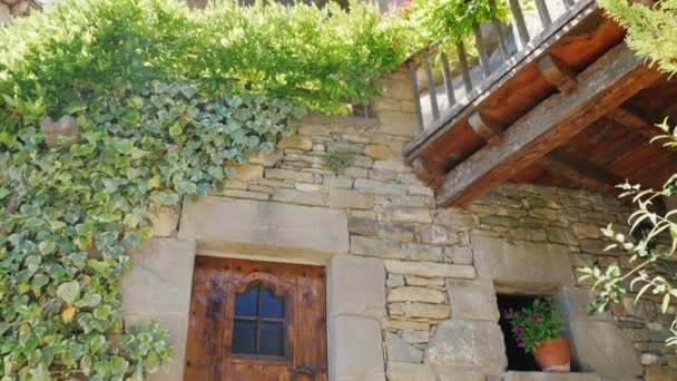 Wooden doors of an old stone house. Nearby are pots of flowers. City Rupit Catalonia — Stock Video