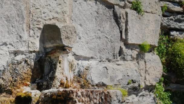 The water flows from the tap in the old stone wall. City Rupit Catalonia — Stock Video