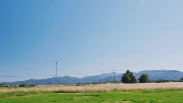 Der Blick aus dem Fenster eines fahrenden Autos. das Auto fährt weiter nach Katalonien, weit gesehen die Berge und Weizenfelder — Stockvideo