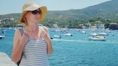 Şapka ve güneş gözlüğü, bir turist boyunca yürüyüş. Yat ve tekne ile defne fonunda görünür Dağları kaldırma.