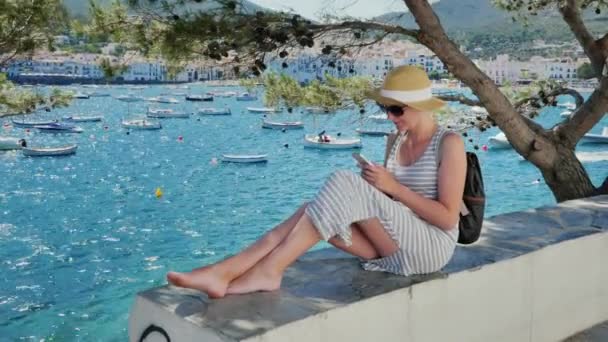 Vinç atış: tekneler ve yatlar koy arka plan üzerinde oturan bir genç bayan. Bir şey Smartphone'da yazmakta olduğunu — Stok video