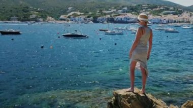 Atış Steadicam: kayalık sahil ve deniz ve İspanya Cadaques resort kasaba güzel manzarasına hayran bir kadın duruyor
