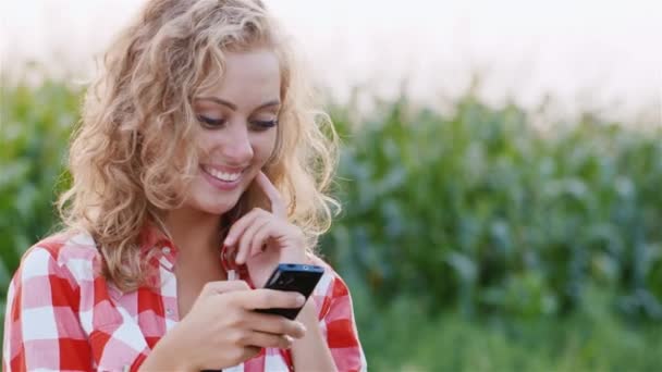 Aantrekkelijke vrouw met behulp van een mobiele telefoon. Platteland achtergrond maïsveld — Stockvideo