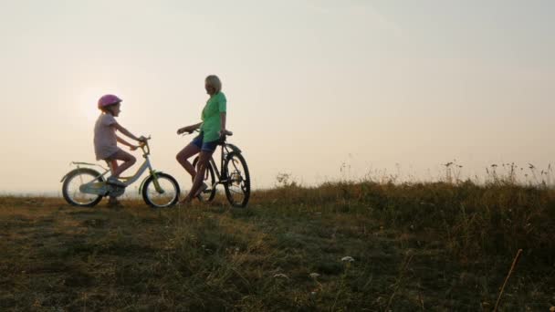 Mamá y el niño se encuentran con la puesta de sol en bicicletas admirando la puesta de sol — Vídeos de Stock