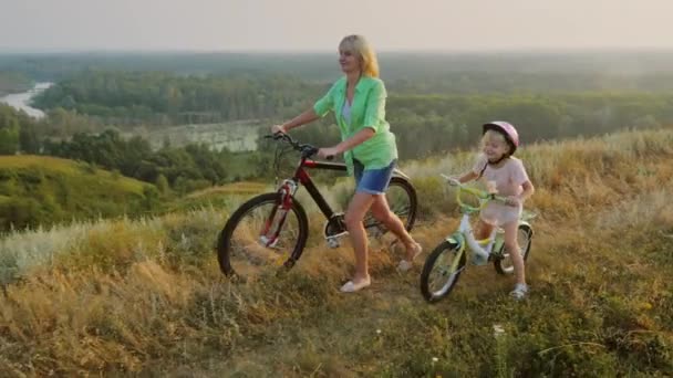 Mutter geht mit ihrer Tochter 5 Jahre. Bleifahrräder, inmitten einer wunderschönen Landschaft — Stockvideo