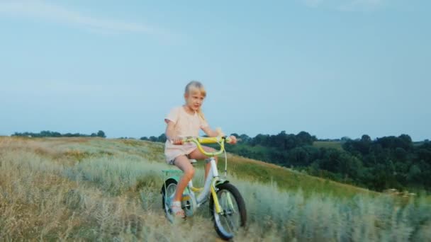 Steadicam tiro: Garota engraçada 5 anos andando de bicicleta pelo campo — Vídeo de Stock