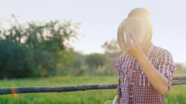Sıcak bir günde bir bira içme bir genç adam. Kırsal kesimde - işçi veya çiftçi bir şapka takıyor