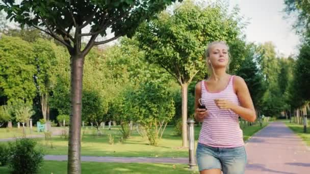 Joven mujer de fitness corriendo en un hermoso parque bien cuidado en una prestigiosa zona de la ciudad — Vídeos de Stock