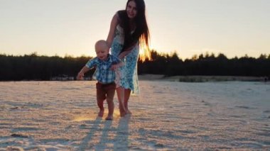 Atış Steadicam: Anne günbatımında küçük oğluyla birlikte çalış. Çocuk fotoğraf makinesi doğru çalışan