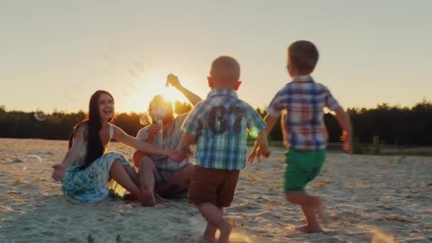 Fiatal család birtoklás móka-val kids - blow buborékok naplemente — Stock videók