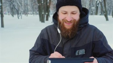 Atış Steadicam: bir kış Park'ta yürüyordunuz çekici sakallı adam sahiptir bir tablet
