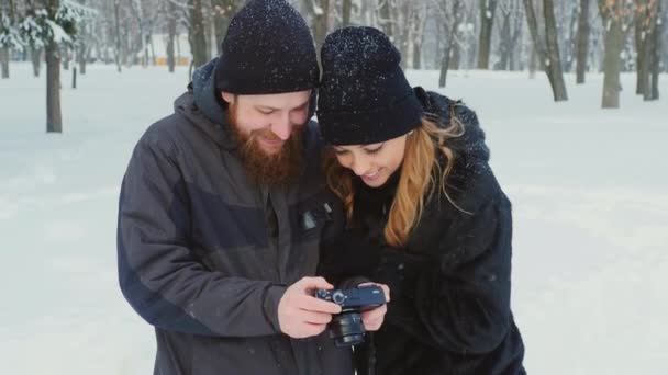 Jovem homem e mulher navegando fotos: quem tinha acabado de filmar no parque de inverno — Vídeo de Stock