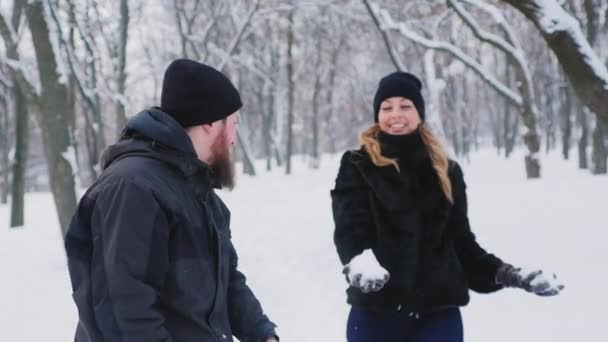 Una joven pareja se mueve en el bosque de invierno, arroja nieve — Vídeo de stock